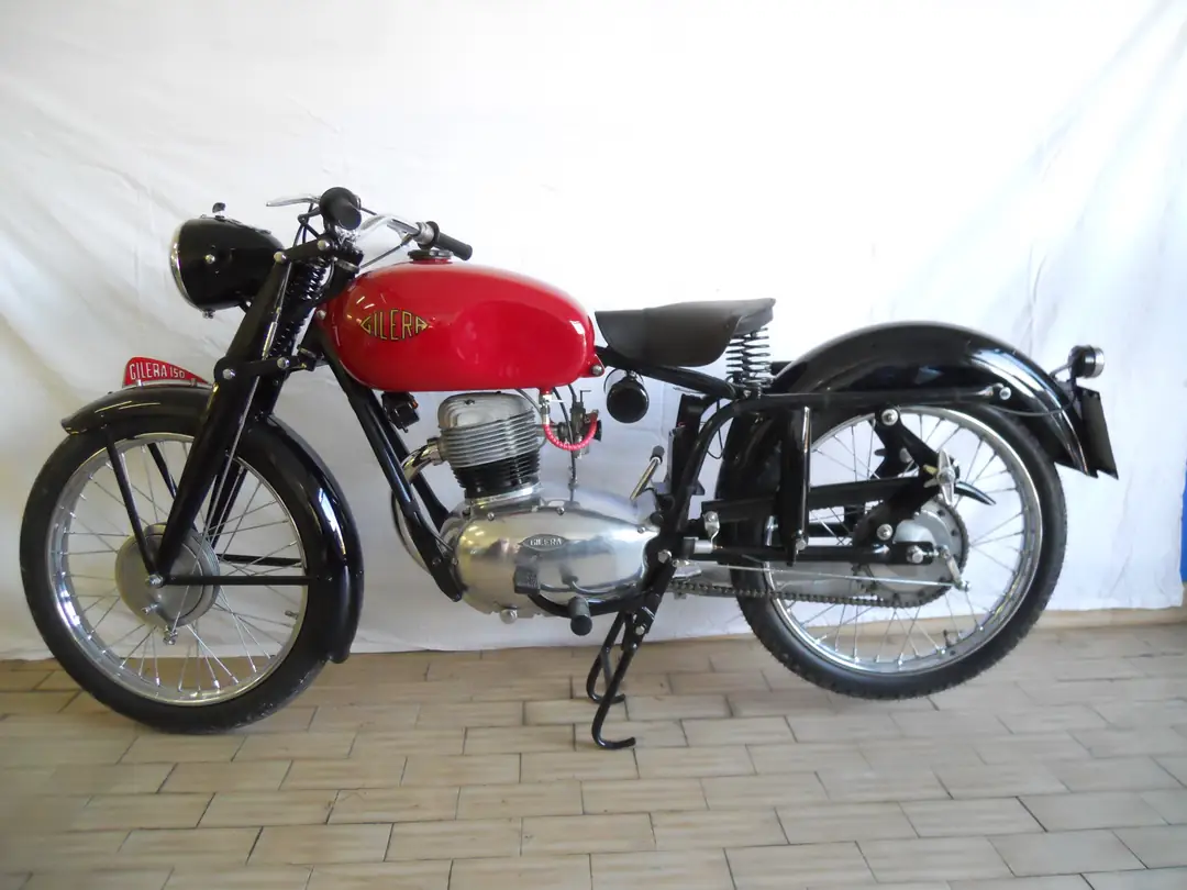 Moto d’epoca rossa con parafanghi neri su fondo bianco