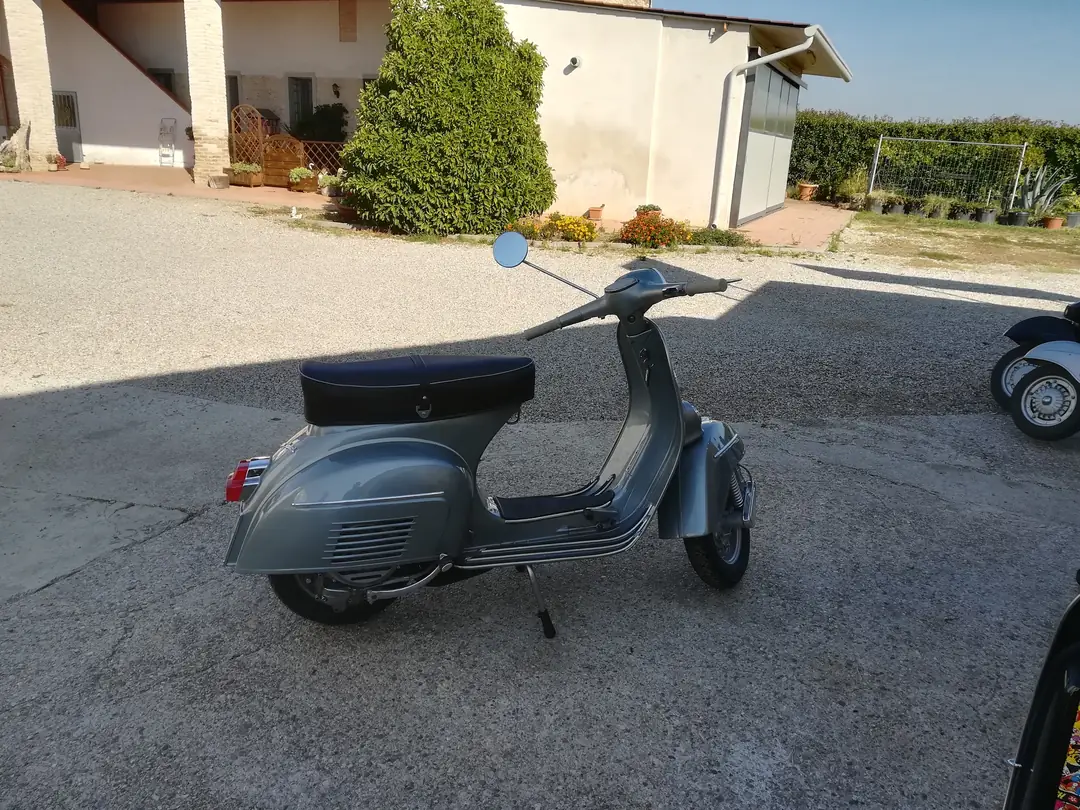 Vespa grigia vista di lato nel cortile dell’officina
